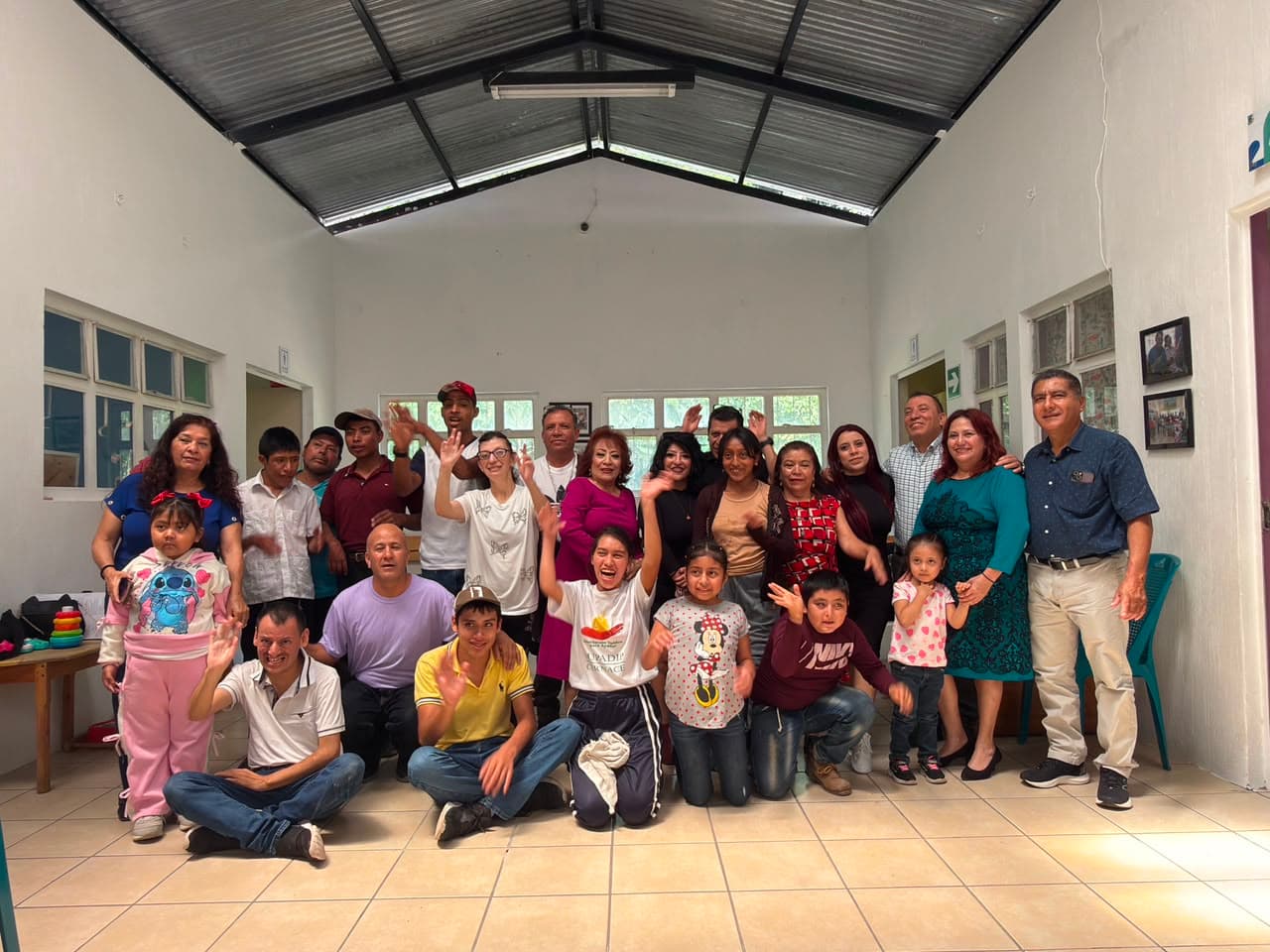 Familias, beneficiarios y personal de CERNACE reunidos en el salón del centro.