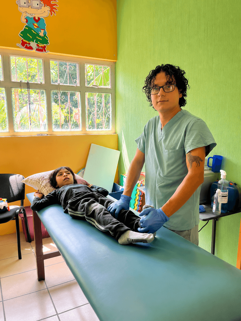 Un terapeuta atiende a un niño recostado en la camilla del área de terapia física.